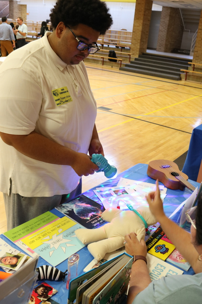 A man wearing a white t-shirt with text on it. He is using toys to learn a lesson in healthcare business.