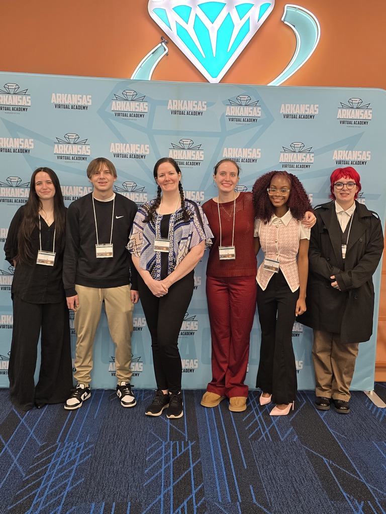 Group of 6 students wearing casual attire posing in front of a backdrop with the Arkansas logo and text.