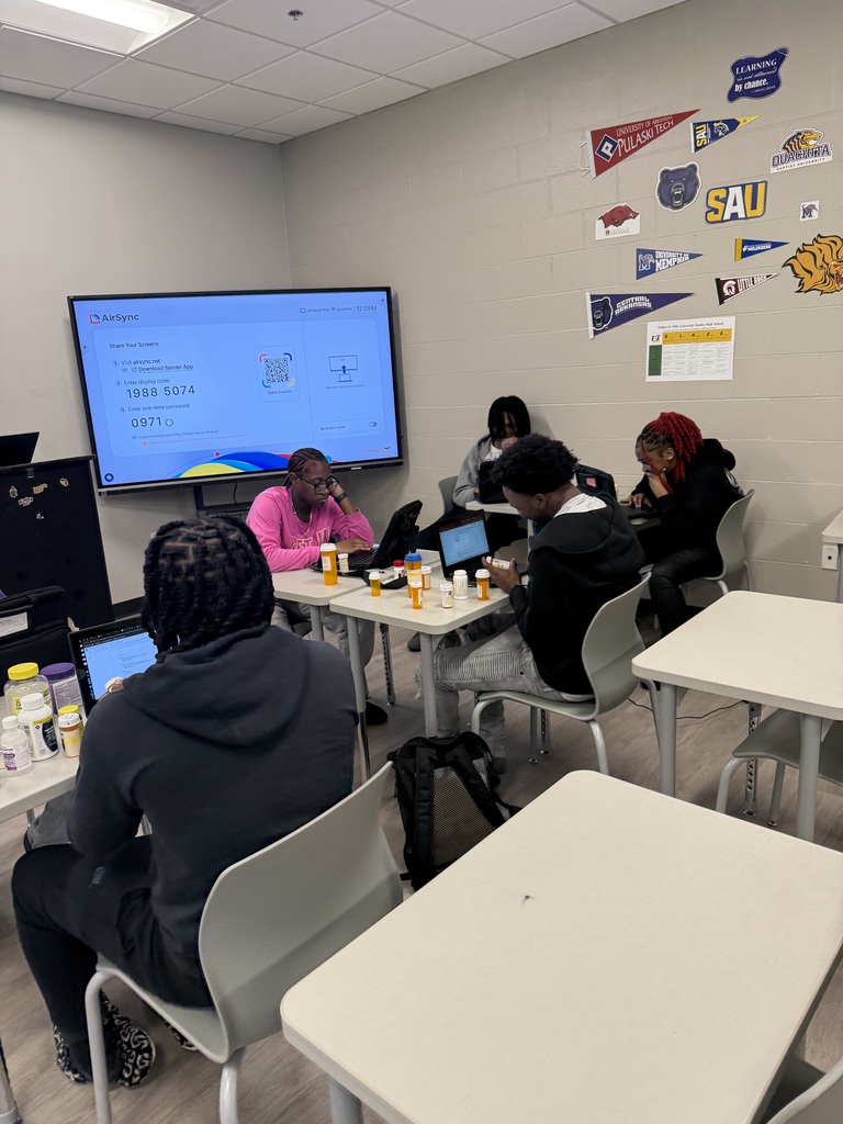 Students in classroom reviewing empty medication bottles.