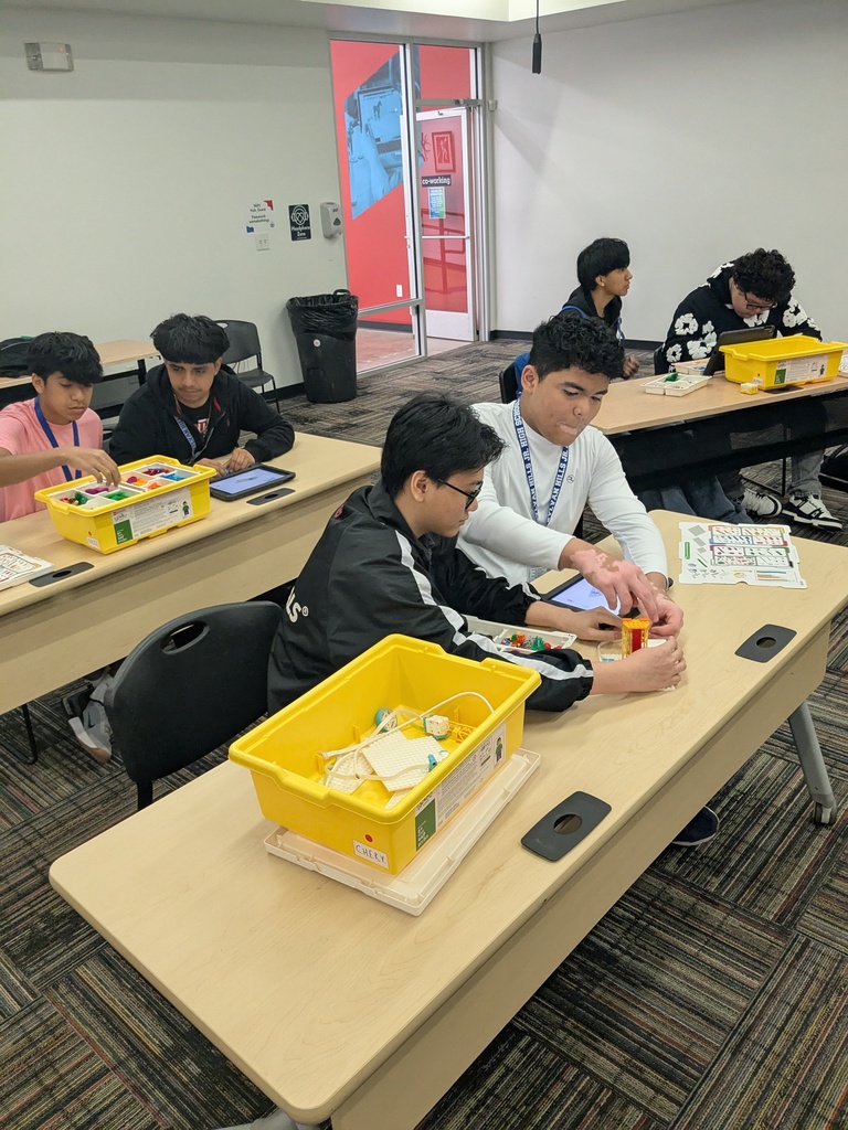 A group of students sitting at desks in a classroom, engaged in various activities and learning experiences.