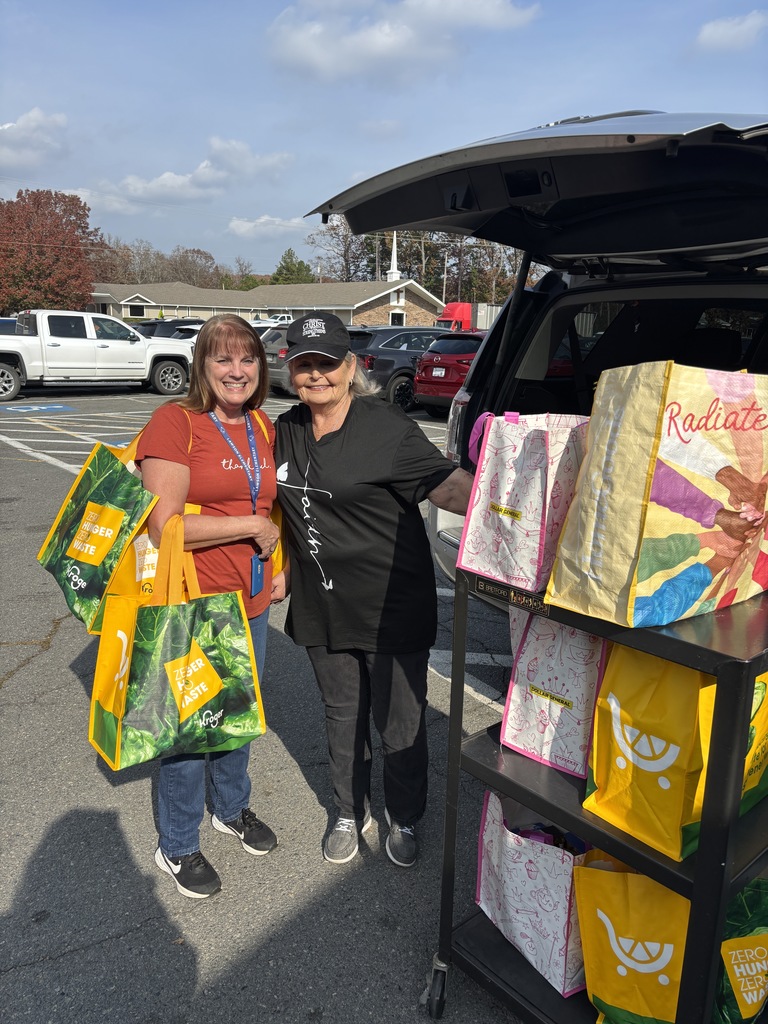 Ms. Cindy (left) with a volunteer from The Church at Rock Creek (right) with nine Thanksgiving Food Bags for families in need. 