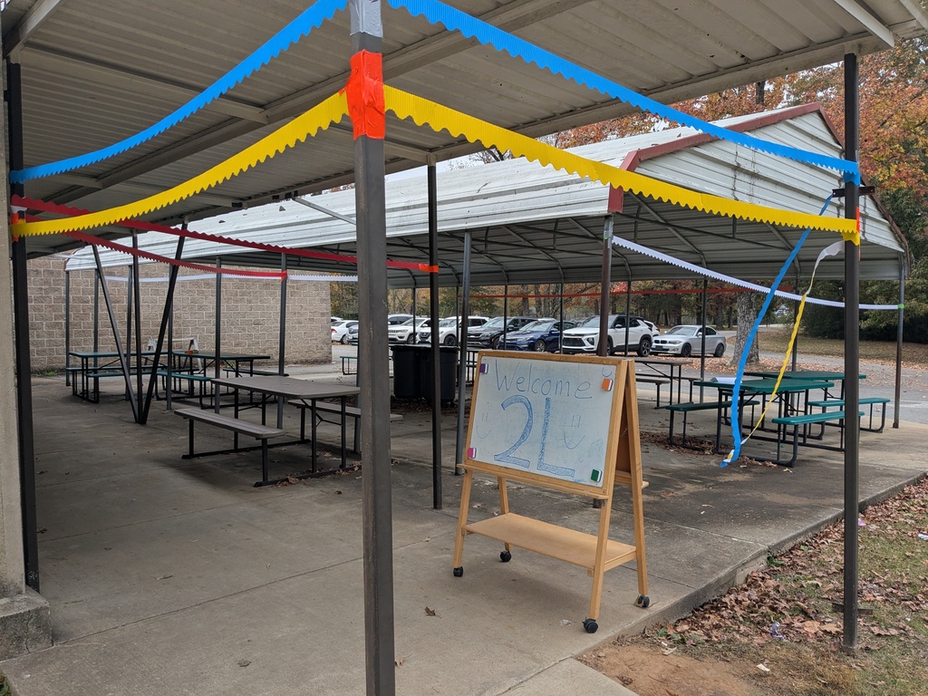 A shaded pavilion with decorations and seating. There is also a sign that says "Welcome 2L".