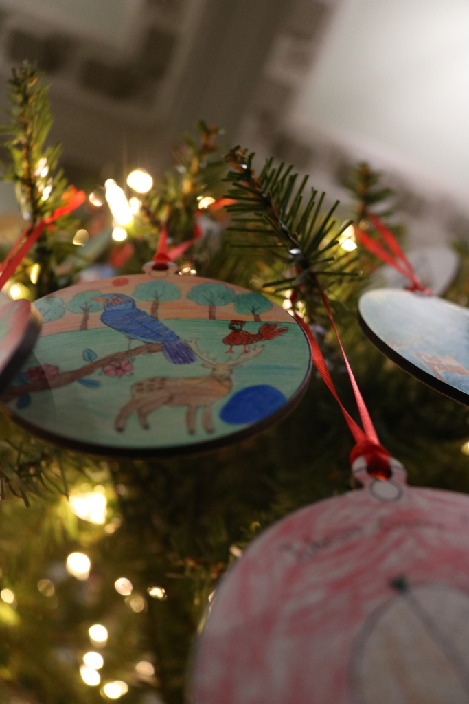 An ornament hanging from a Christmas tree. It shows an artist's rendition of a wildlife in a forest clearing