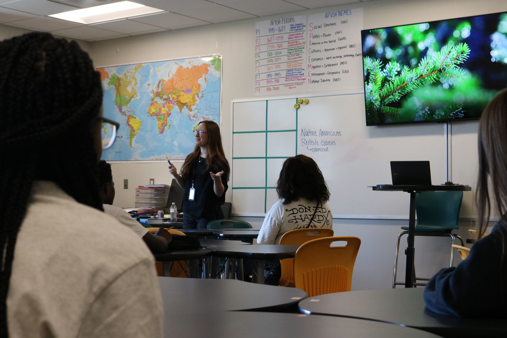 Classroom with world map, whiteboard, and students working at desks.