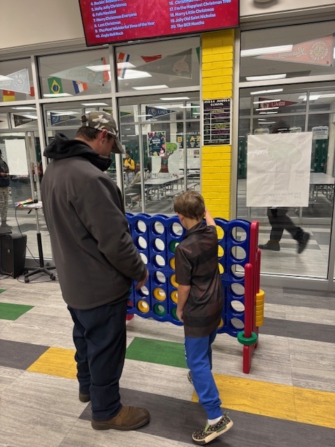 father and son play large connect four at Book Fair Family Night