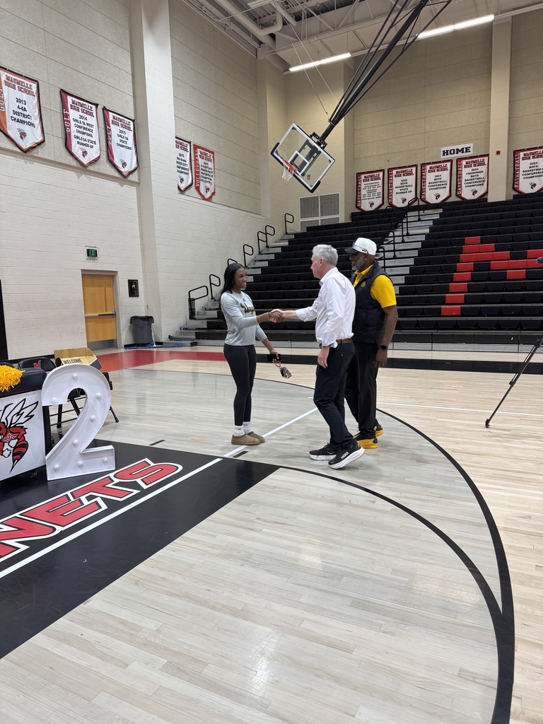 A woman shaking a older man's hand in a gym.