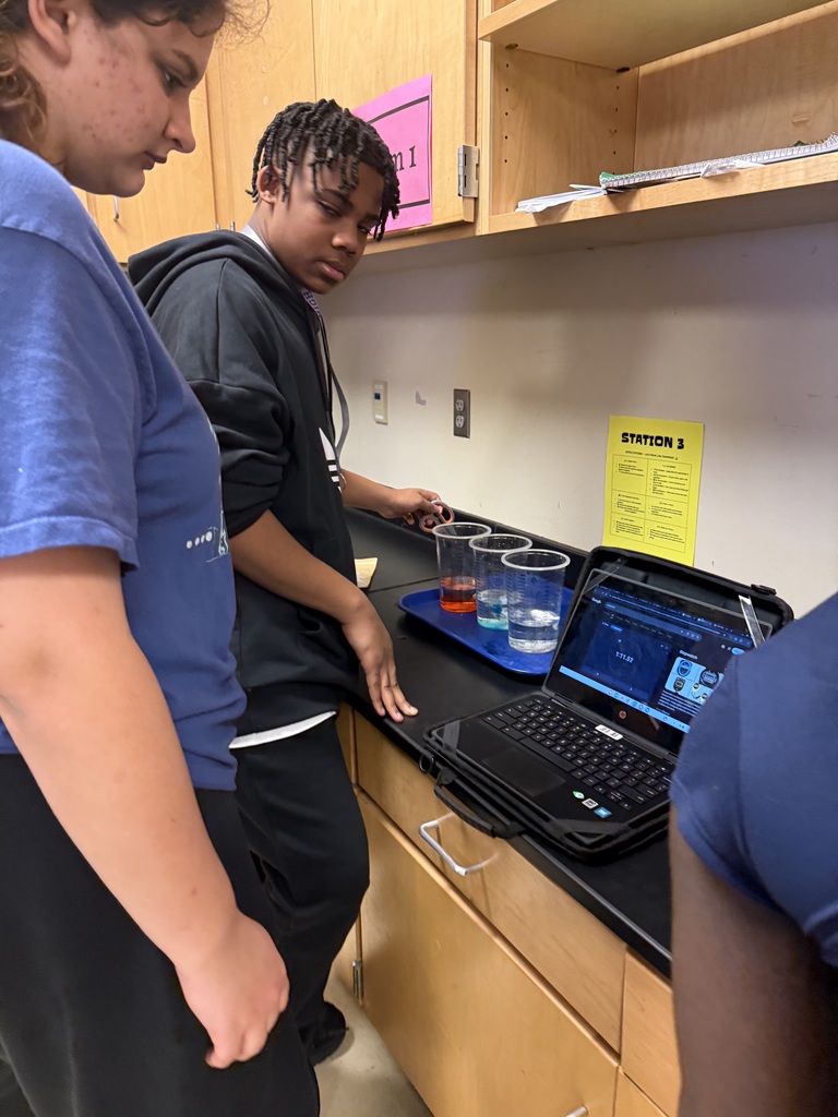 Two young people using a laptop and looking at something on the computer screen in a lab setting.