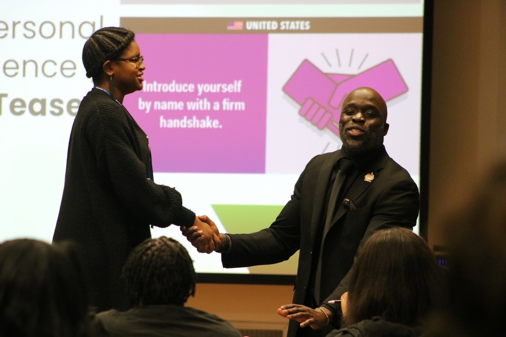 Motivational speaker using a student as a demonstration of how to do a firm handshake