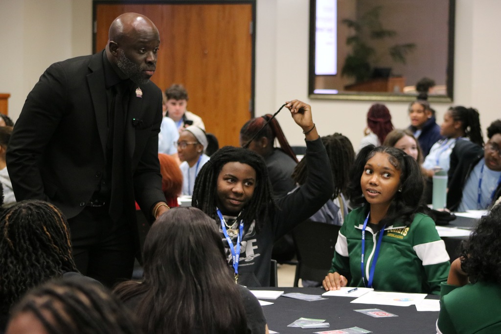 An older man speaks to children sitting at a table