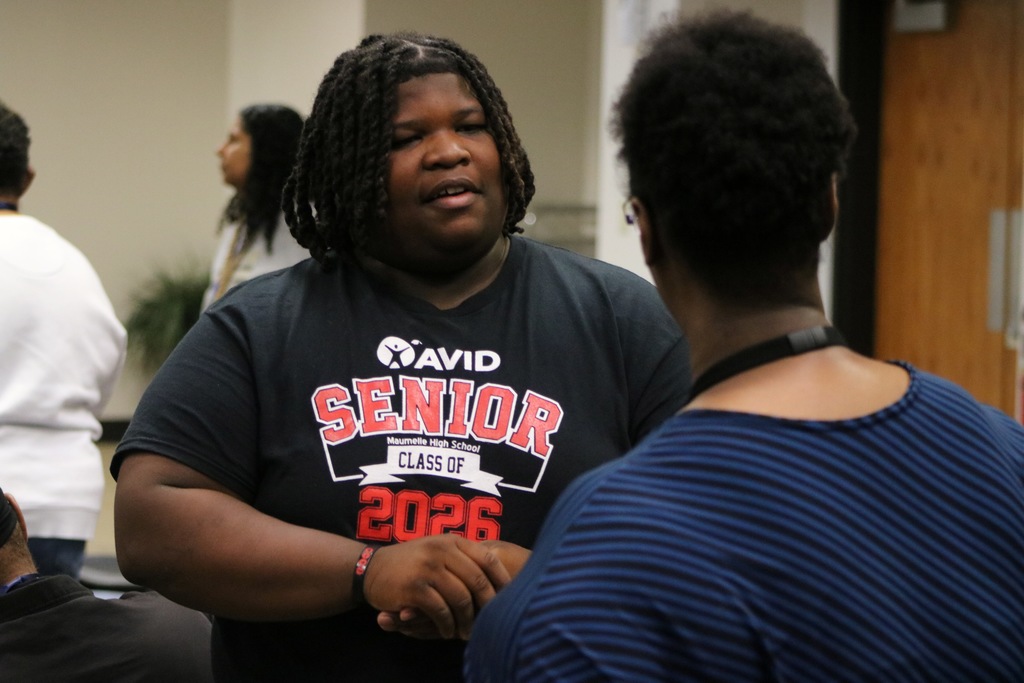 Student in an AVID SENIOR CLASS OF 2026 Maumelle High School shirt talking to a teacher