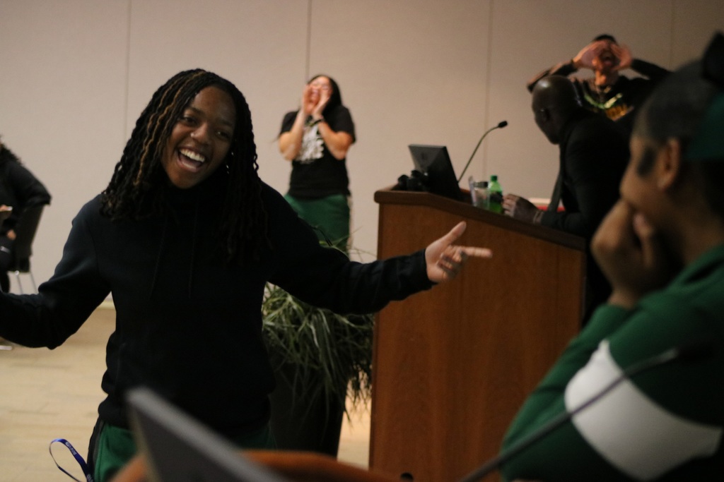 Kid smiling as other kids cheer in the background