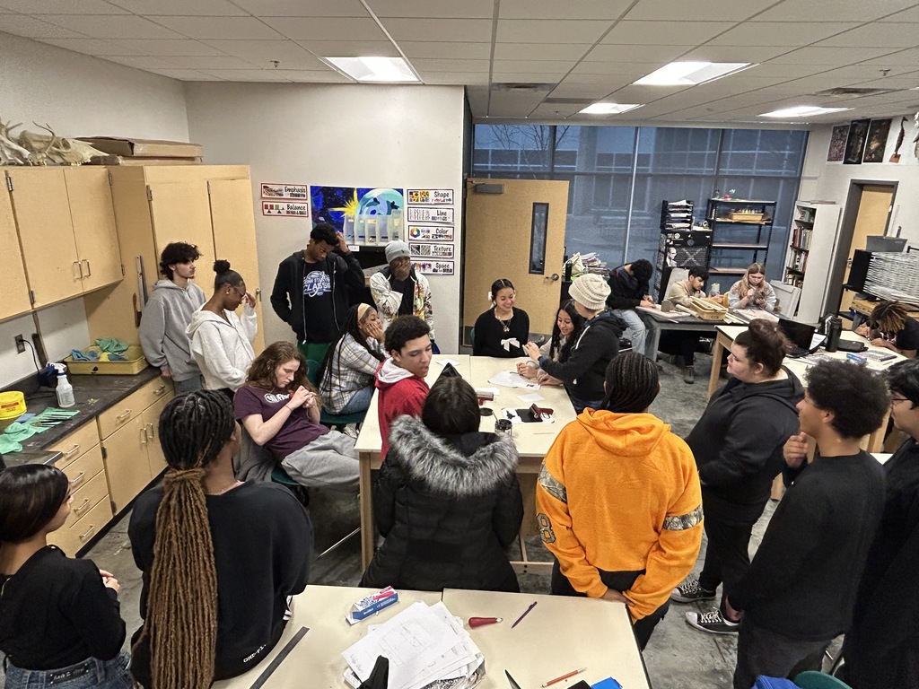 Art teacher demonstrating printmaking to a group of students
