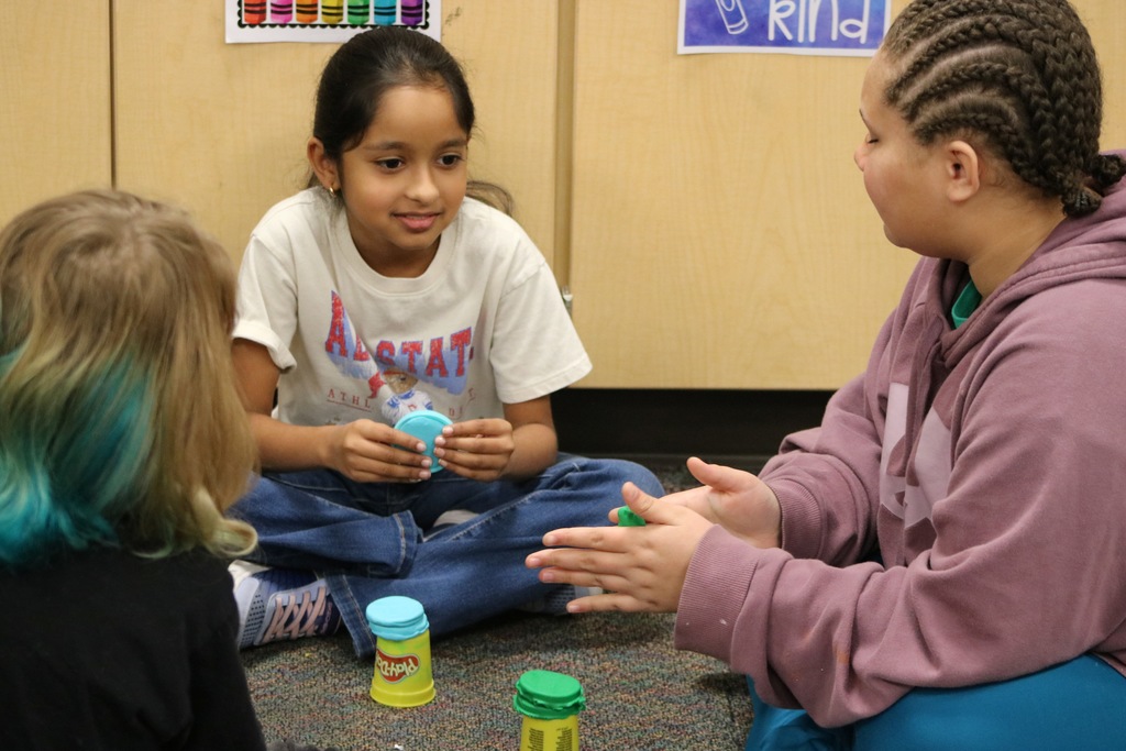 kids sitting on the floor playing with Playdoh