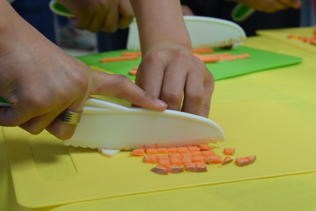 A close up of a student cutting a sweet potatoe