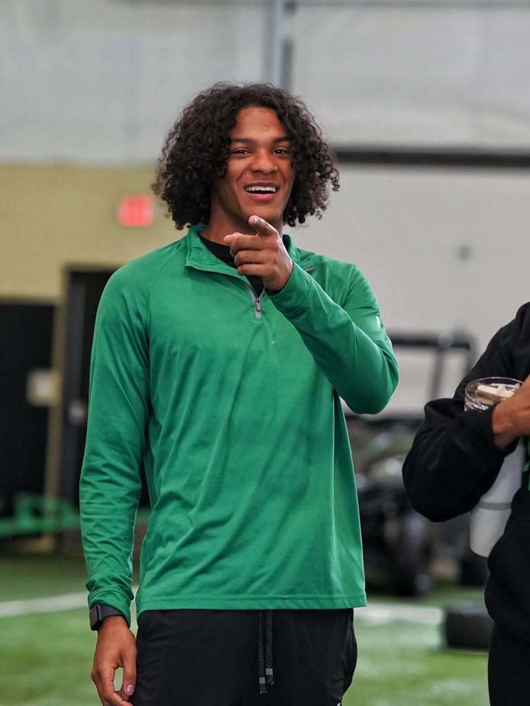 A smiling Joe T. Robinson football player pointing at the camera.