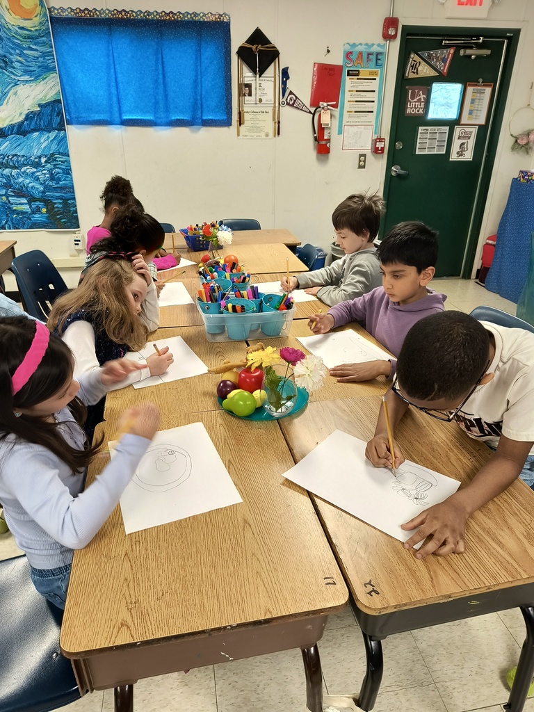 2nd grade practice Still Life drawings. Several students with pencil and paper sitting at a table drawing fruit and flowers.