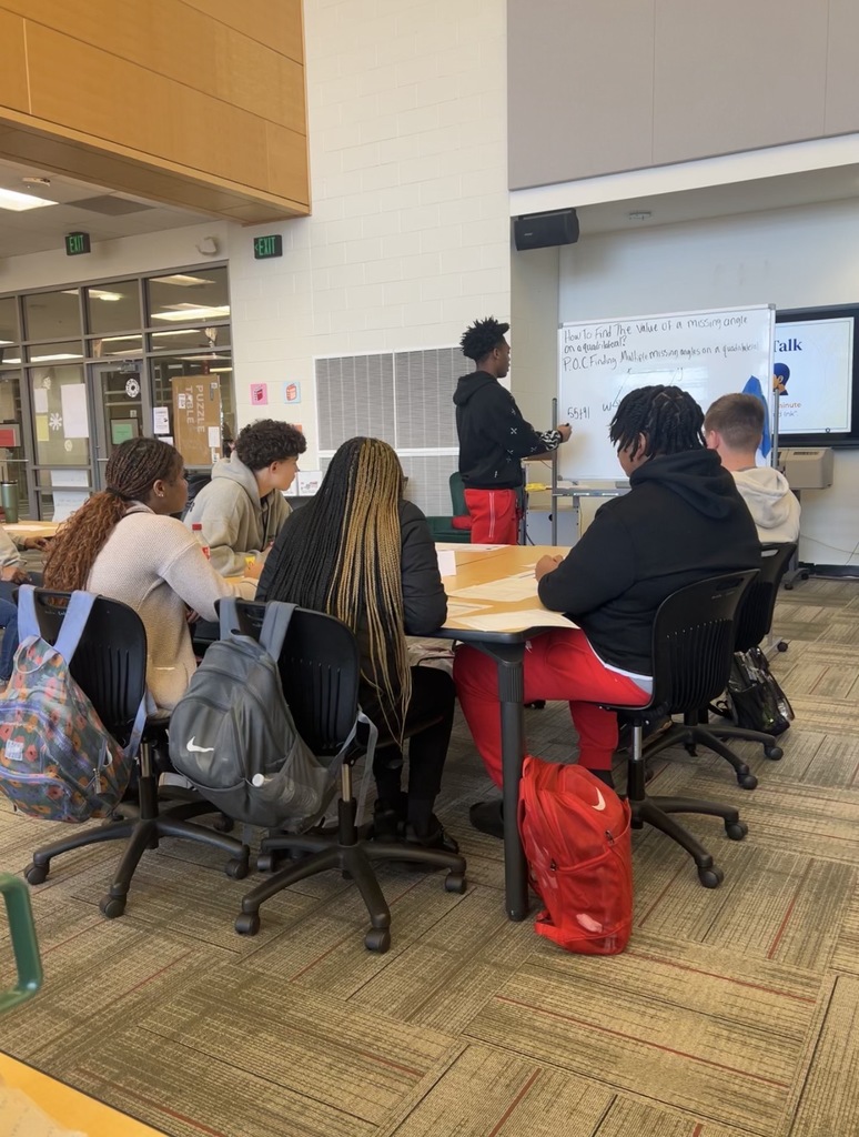 Maumelle High student standing at whiteboard with five other students seated