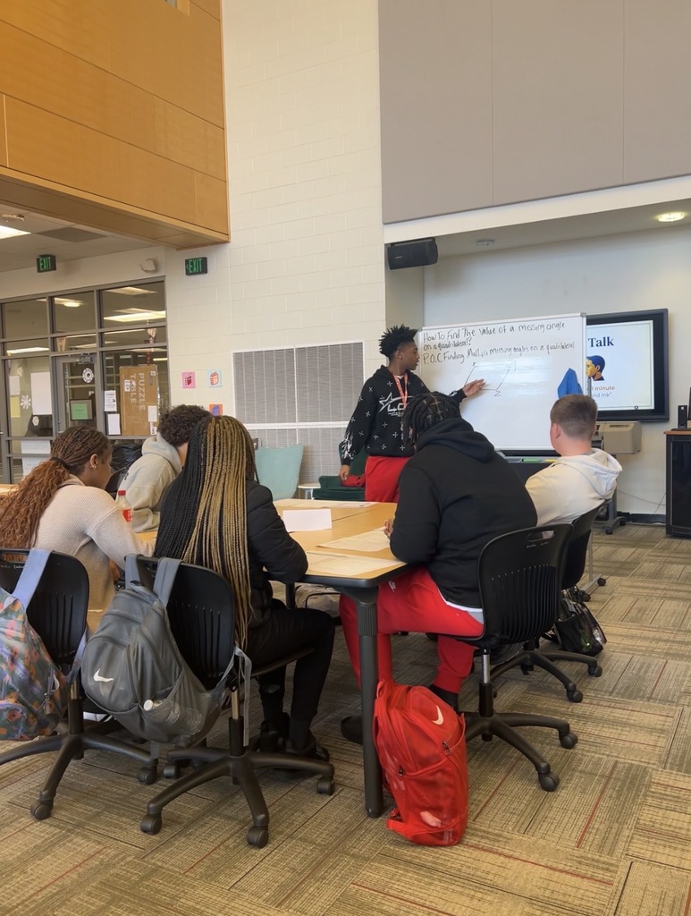 Maumelle High student standing at whiteboard with five other students seated