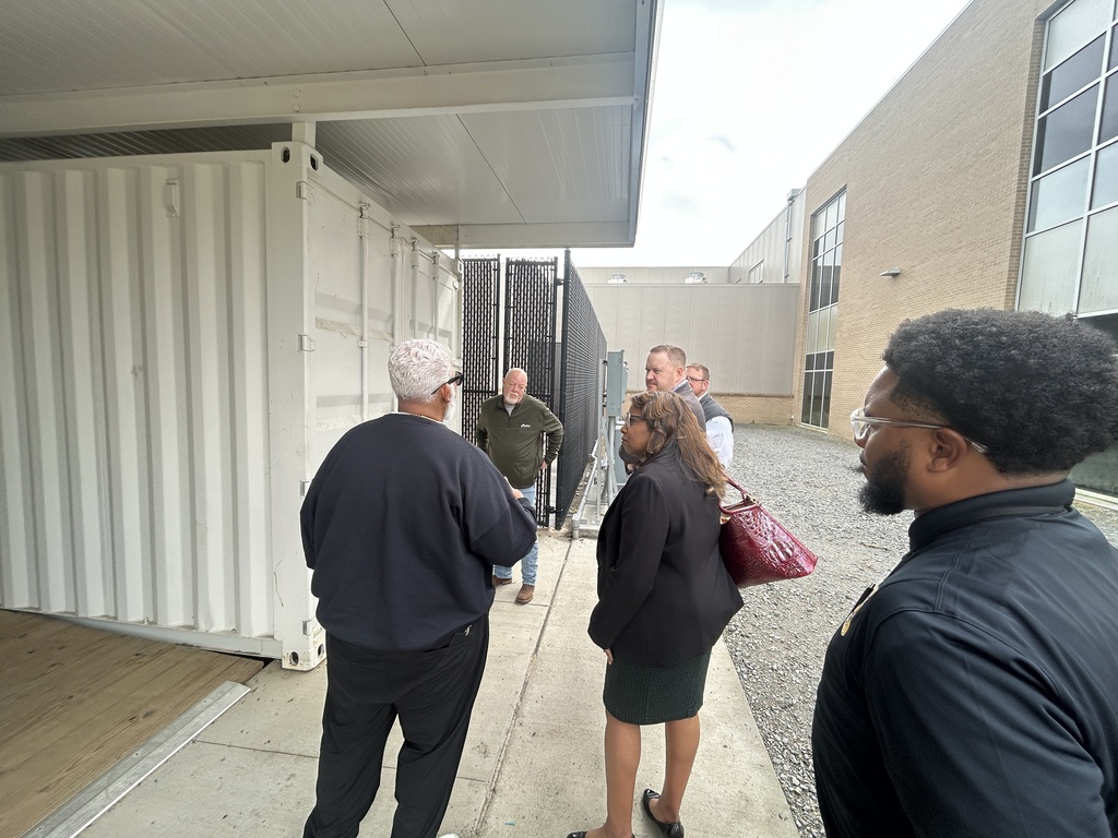 Adults standing near the welding con-ex building