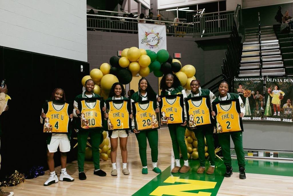 Seven senior from the Mills Lady Comets basketball team hold framed jerseys