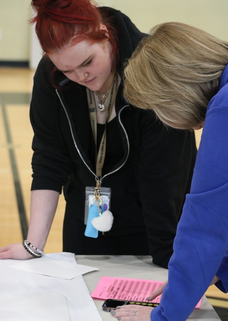 A girl and woman having a discussion about her budget. They are both leaning over a table.