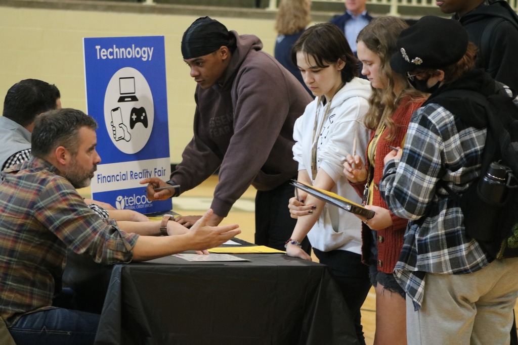 Students having a discussion about technology while budgeting at a table.