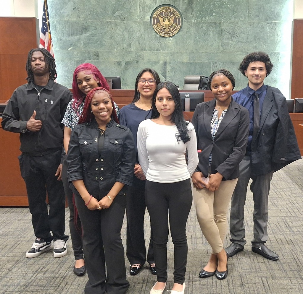 A group photo inside a courtroom. There are seven people in the photo. Five in the back. Two in the front.
