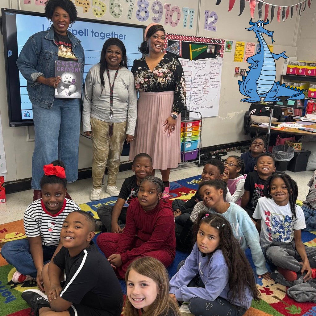 Students and adults smiling for the camera in a College Station classroom. One adult is holding the Creepy Crayon book.