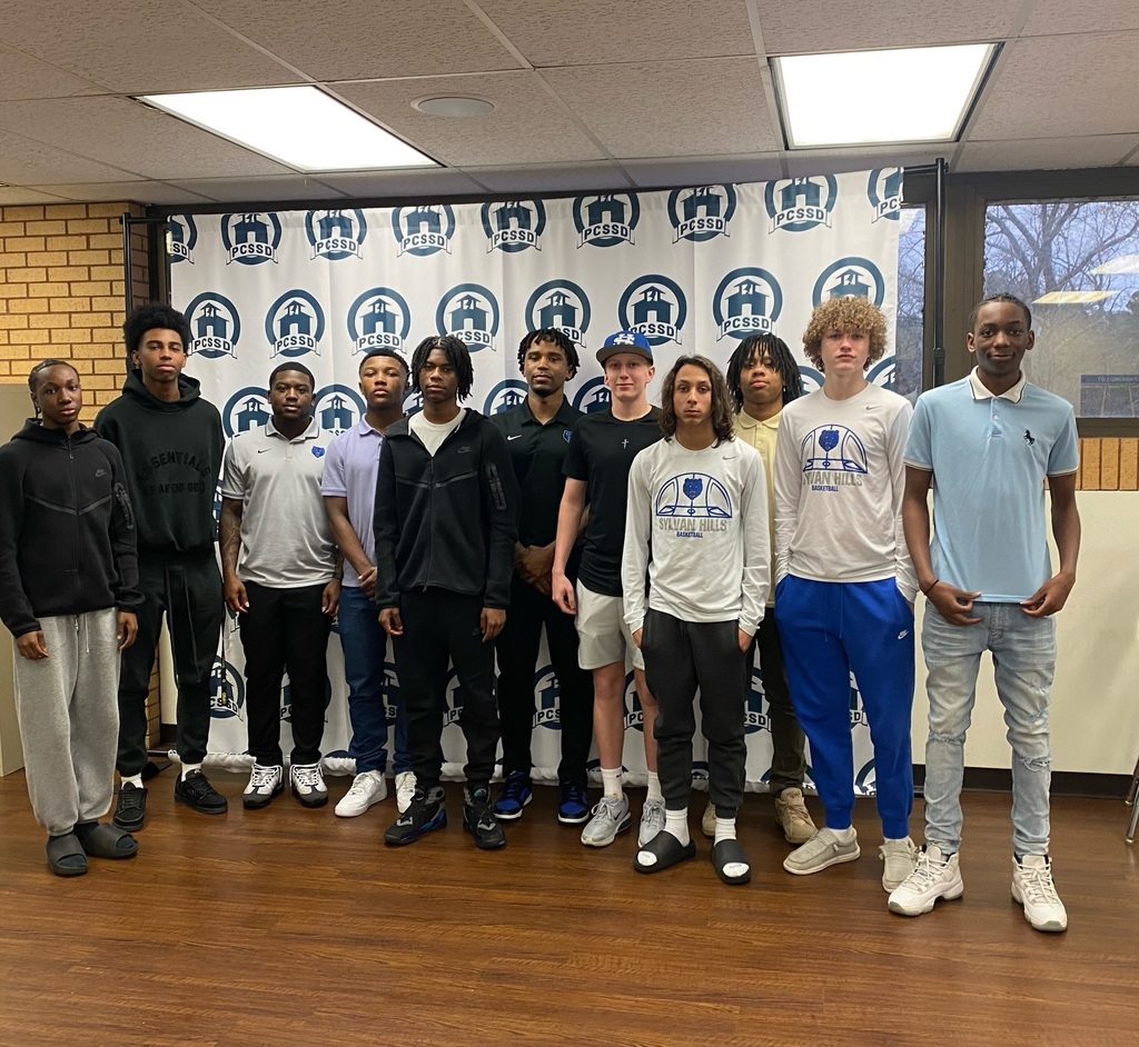 Sylvan Hills Jr. High Basketball team at the PCSSD Central Office in front of a branded backdrop