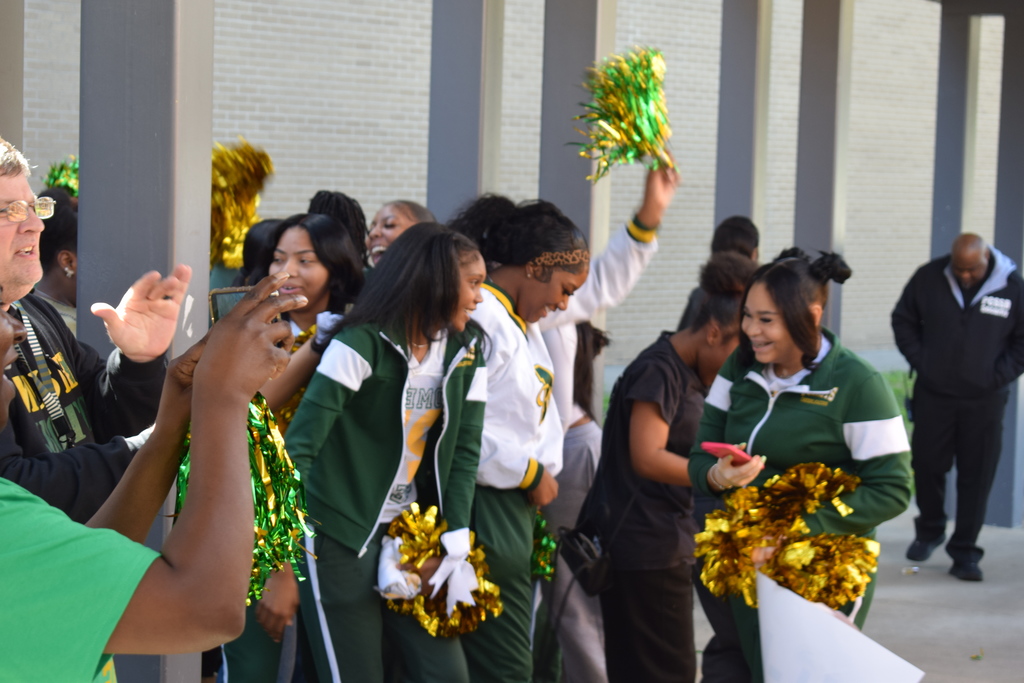 Students cheering with pom poms outside.