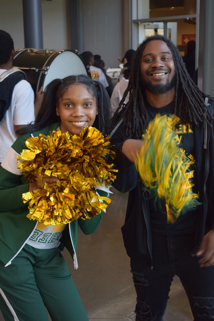 Two people holding pom poms and smiling toward the camera.