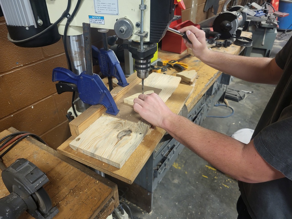 RHS students drilling pre-spaced holes with a template. 