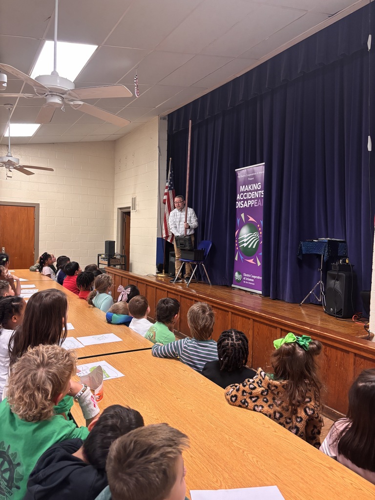 Scott Davis in front our Lawson Students explaining what his show is all about (electrical safety). He is on stage with a banner behind him that reads "making accidents disappear". He is pulling an electrical pole out of his toolbox. 