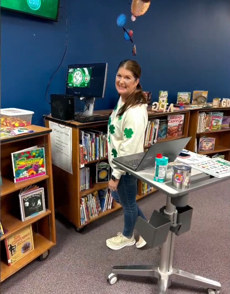 A digital display shows a green St. Patrick’s Day–themed bingo game titled “St. Patrick’s Bingo!” with numbered balls, a list of callouts, and a “Winner!” button on the screen.