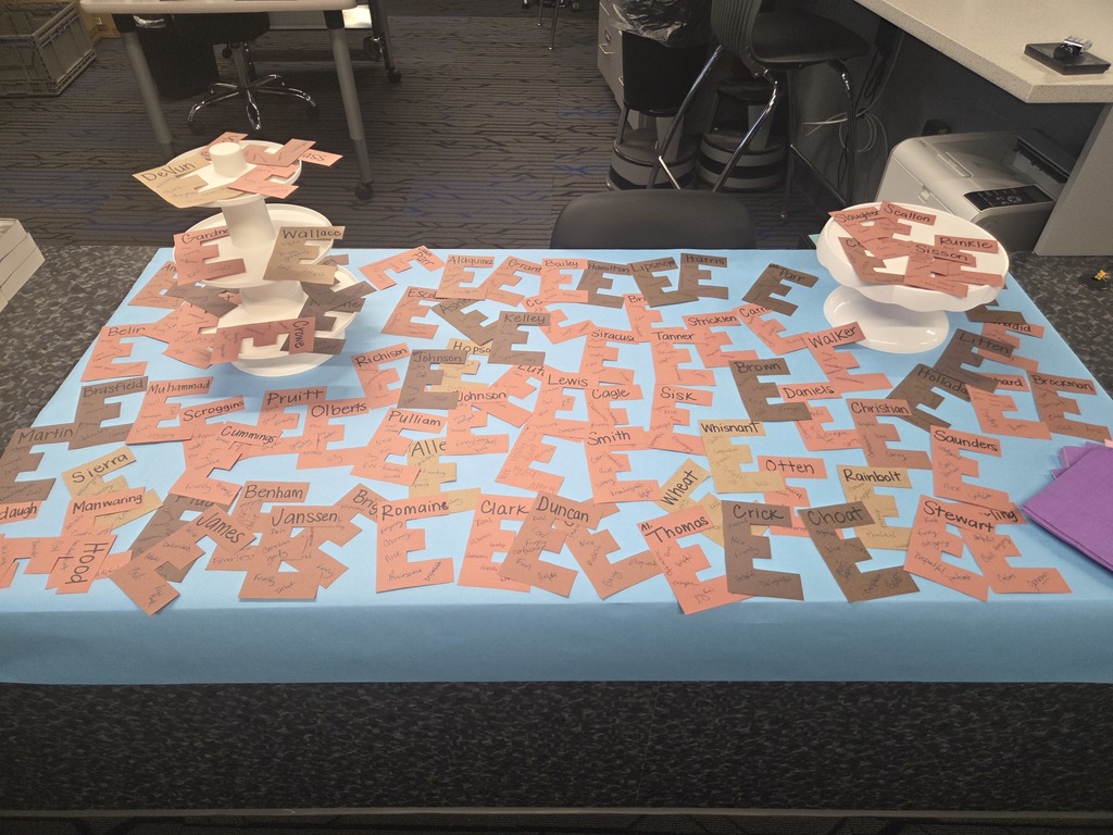 A wrapped table with cake sheets filled with brown paper cutouts of the letter 'E', creating a visual pun for 'brownies' for an April Fools' joke