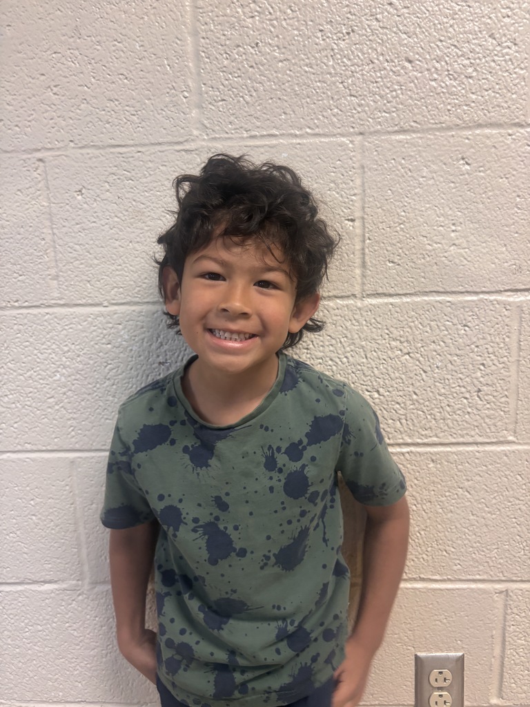 Image of Kindergarten Student who was nominated for Student of the Month. He is wearing a green t shirt with blue spots. 