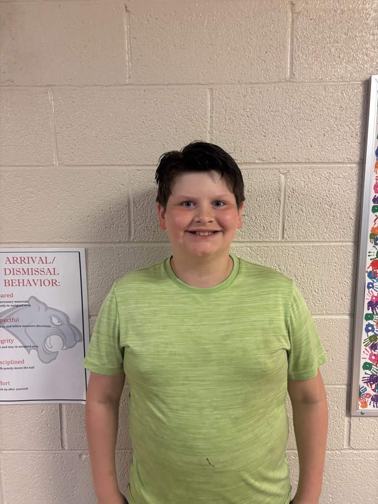Image of fourth grade student who received student of the month. He is wearing a green t shirt. 