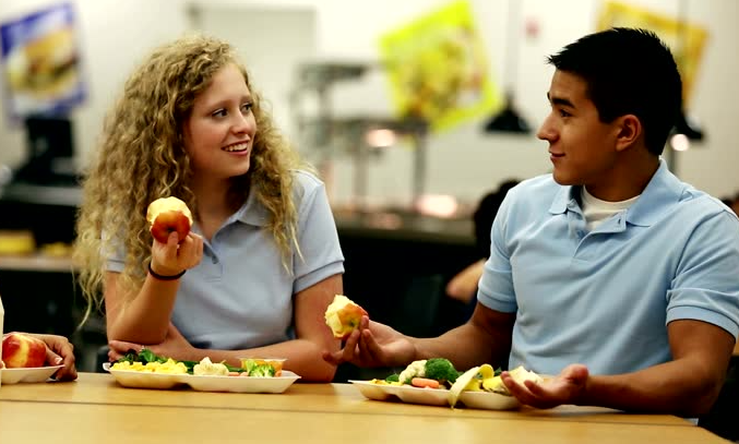 Two teens eating school meals