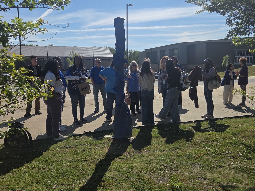 Students and adults gathered around the new Peace Pole in the Sylvan Hills High School courtyard, smiling and admiring the new installation.