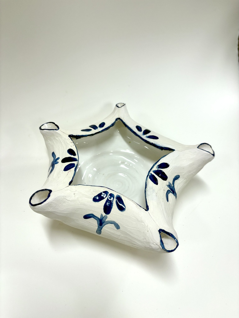 A star‑shaped ceramic bowl with five points, glazed white with blue hand‑painted floral patterns along the edges and sides.