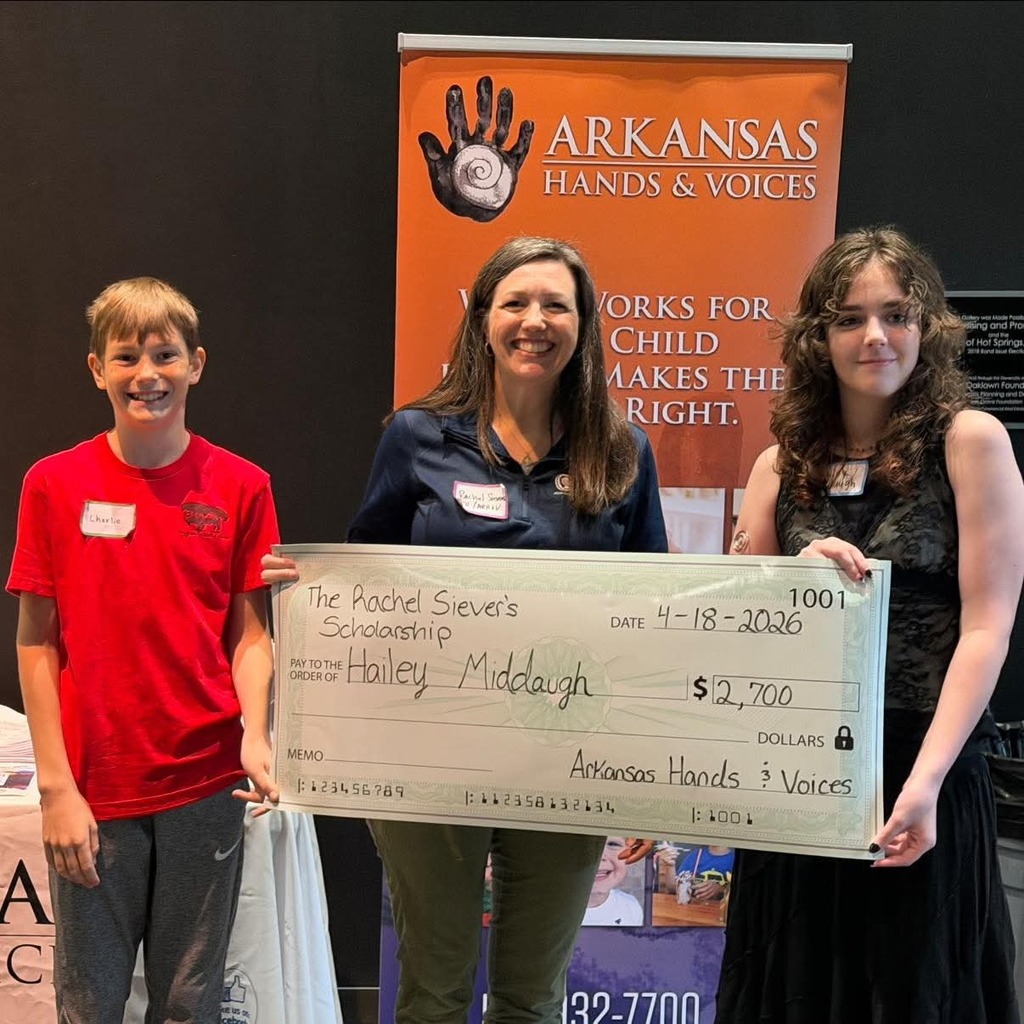 Three people stand together smiling as senior Hailey Middaugh holds a large ceremonial check for the Rachel Sievers Scholarship.
