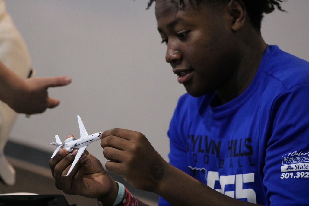 A student holds a detailed model jet labeled “Falcon"