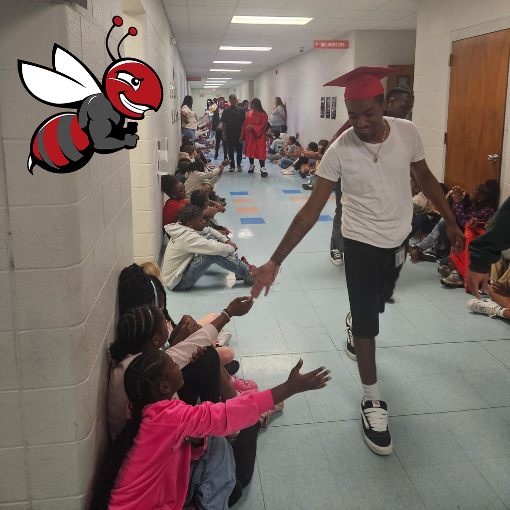 An older student in a graduation cap high fiving younger students.