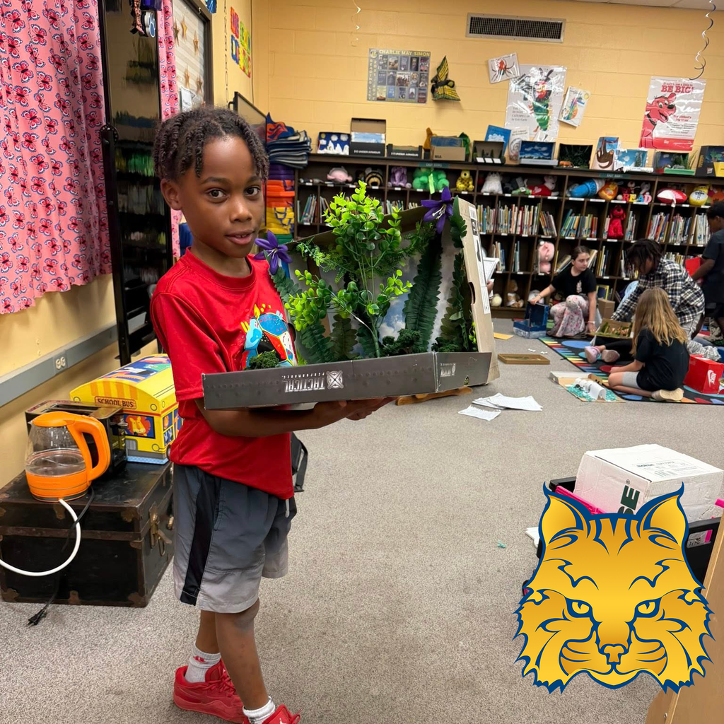 A student holding a diorama project. The Oakbrooke Elementary logo is in the corner.