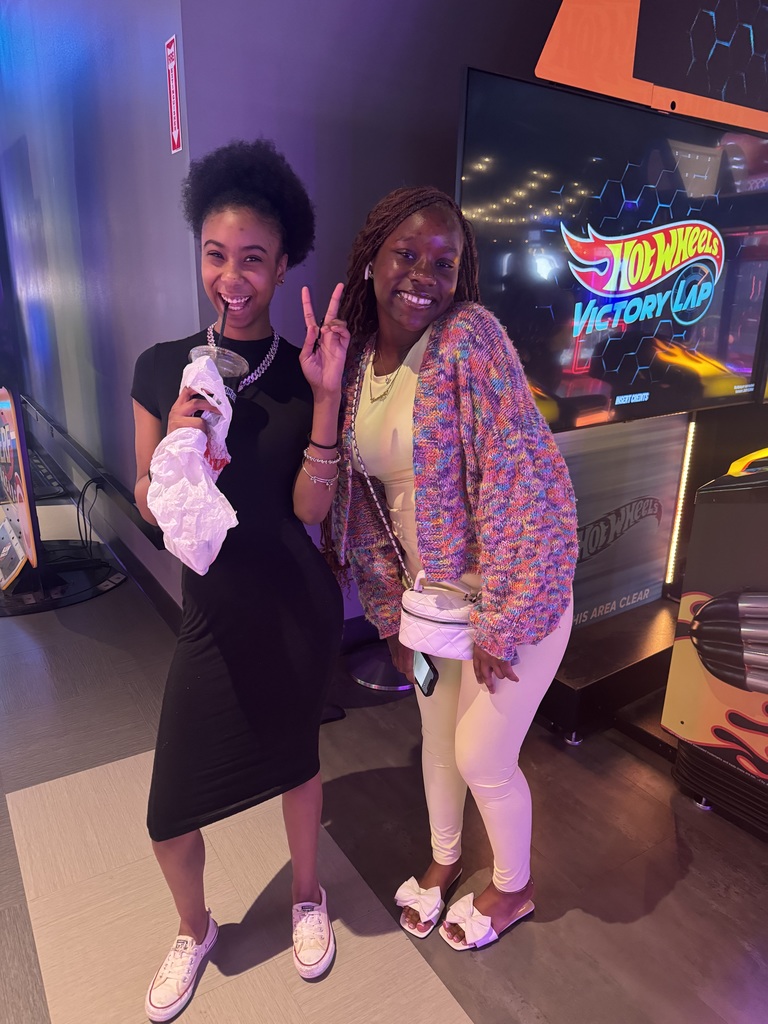 Two students who are smiling near a video game