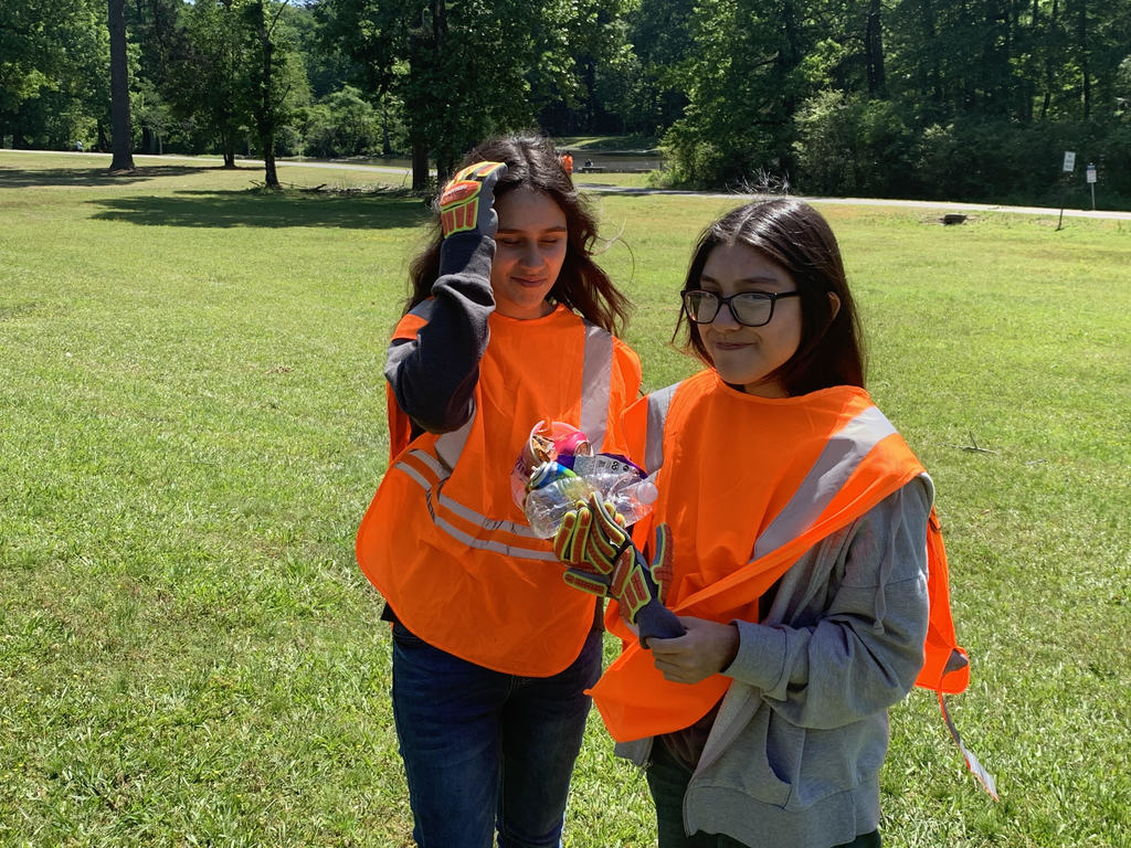 Two students in safety vests picking up trash