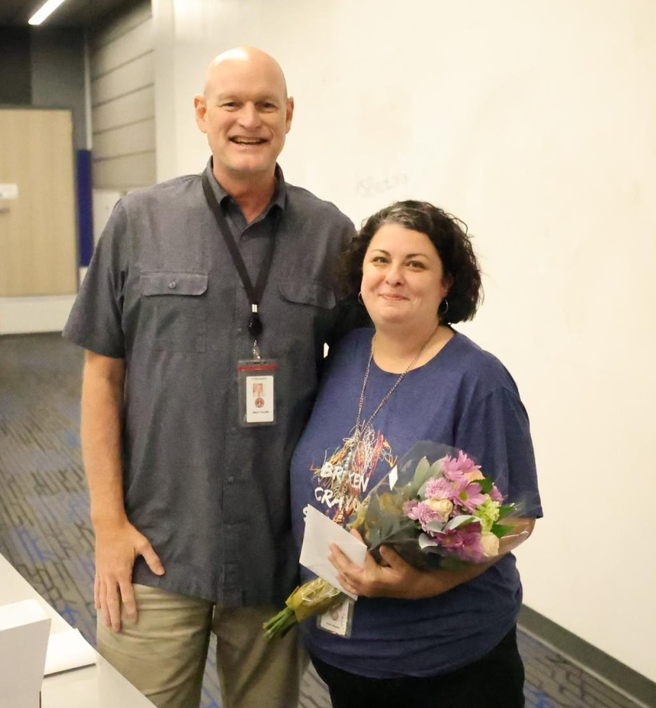 Sylvan Hills High School Principal Tracy Allen and Ciara Cole stand side by side smiling. Cole is holding a bouquet and envelope.