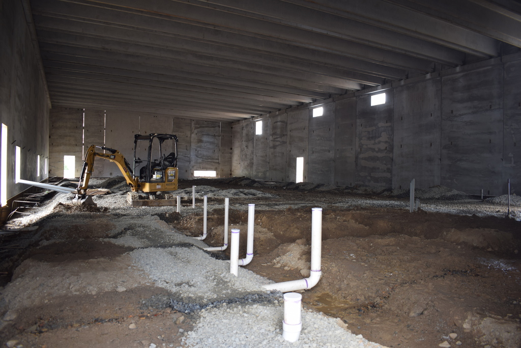 Inside the new Joe T. Robinson High School addition, construction crews prepare plumbing and groundwork in a large unfinished building space.
