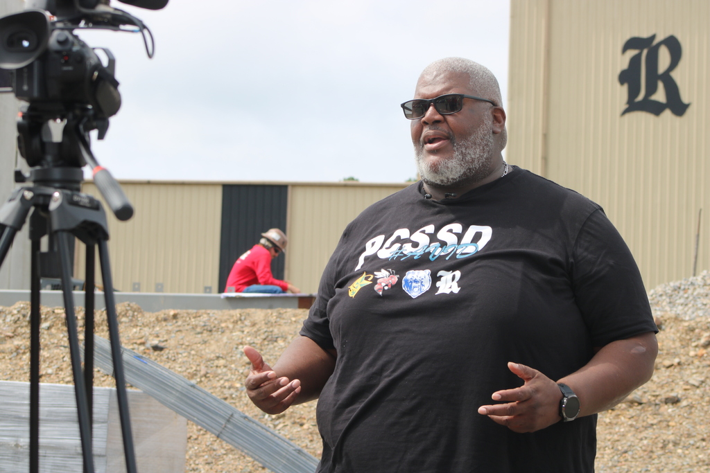 A PCSSD staff member speaks on camera at the Joe T. Robinson High School construction site during the topping out ceremony.