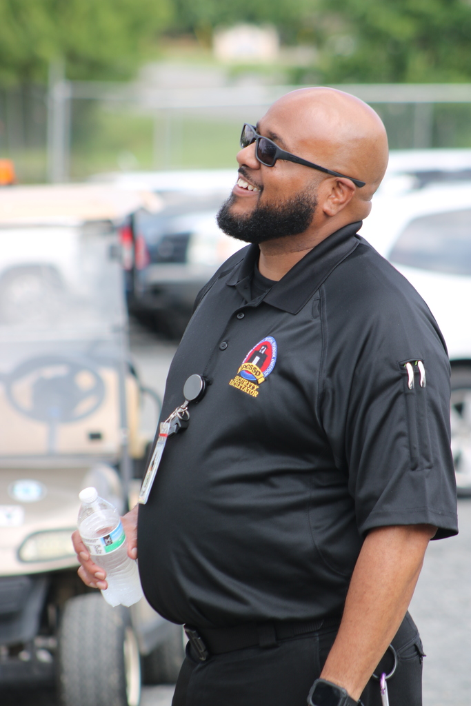A PCSSD employee watches the Joe T. Robinson High School topping out ceremony while holding a water bottle.